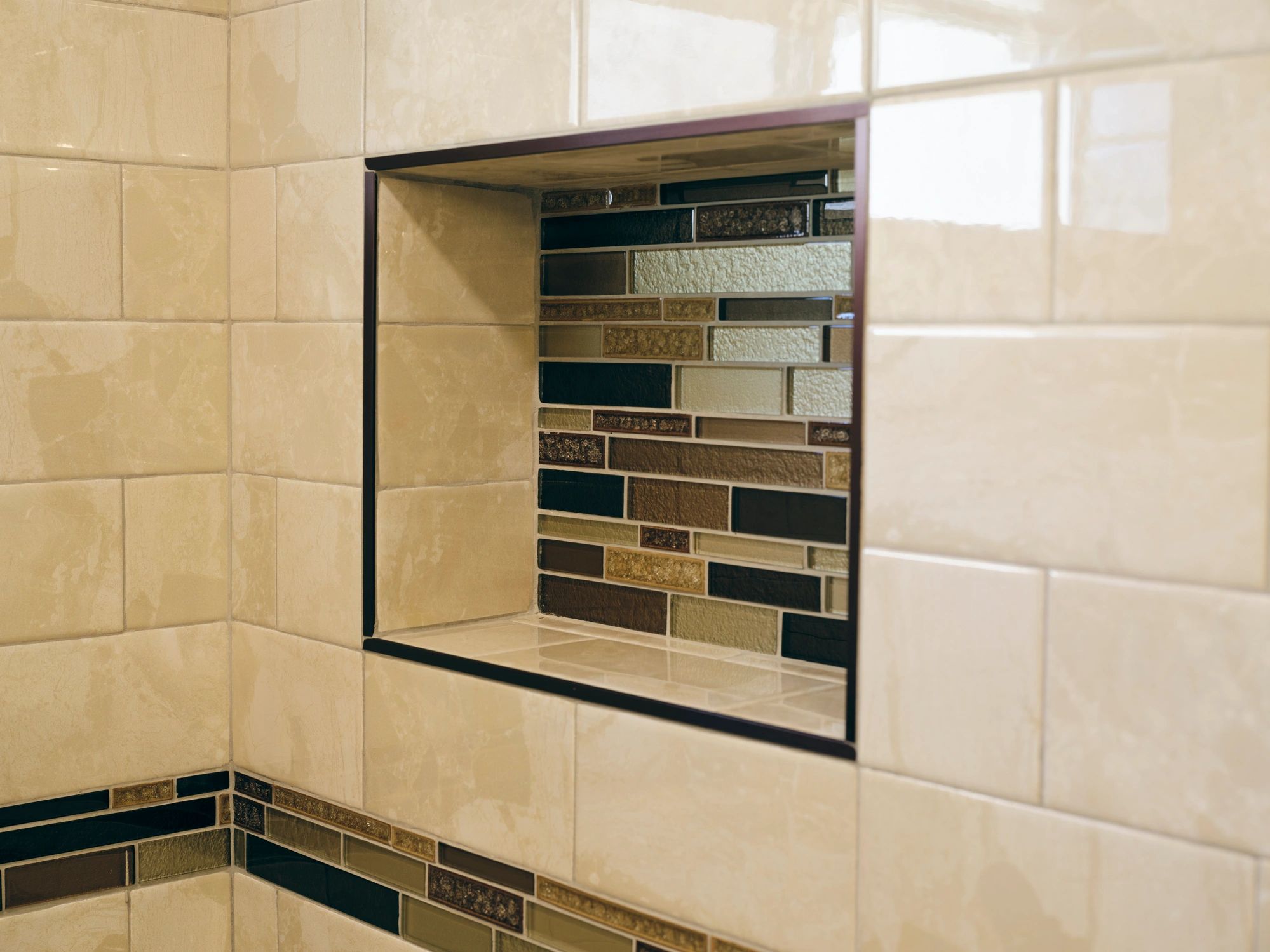 Tiled shower wall featuring a decorative recessed niche.
