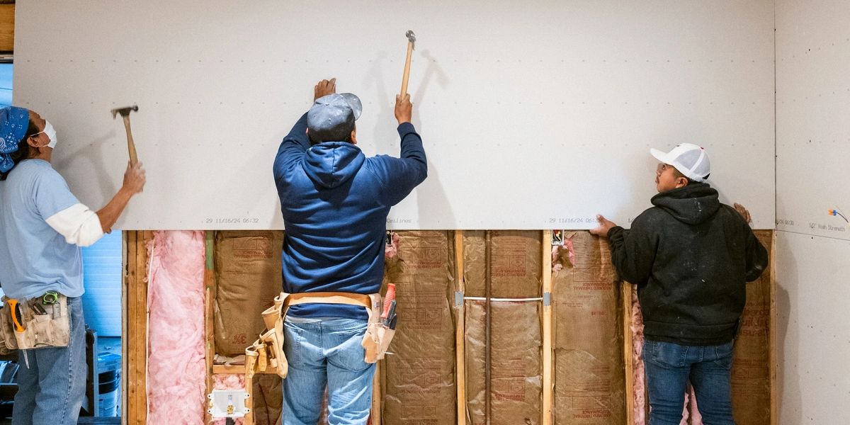 Workers installing drywall on a residential construction site.